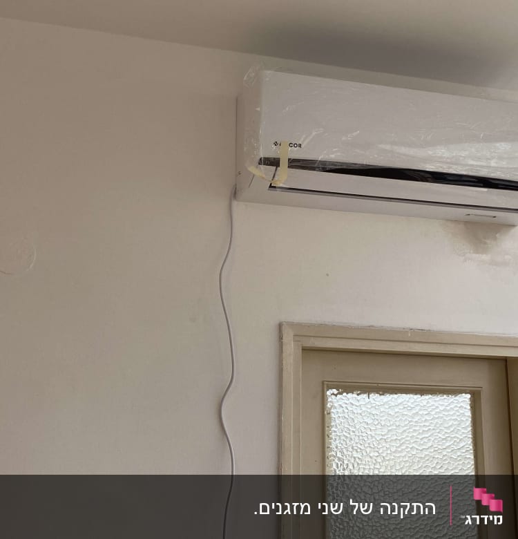 מזגן מותקן על קיר עם כבל חשמל תלוי